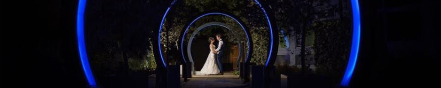 Married couple pose for photo between arches